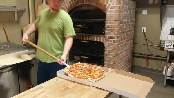 James taking the pizza out of the brick oven.