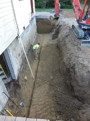 Digging a new basement along an existing foundation for a new addition.