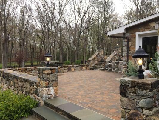 Brick patio with field stone walls and bluestone steps. Fieldstone pillars with integrated lighting.