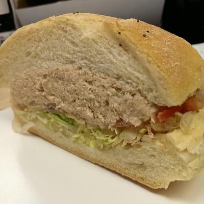 Tuna on a roll with lettuce and tomato.