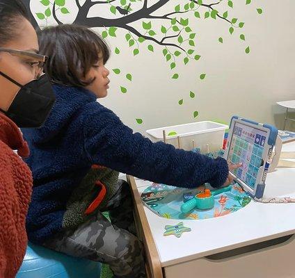 Child using AAC during therapy.