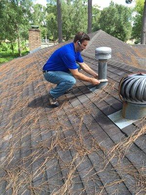 Inspecting a loose rain cap for the furnace flue vent.