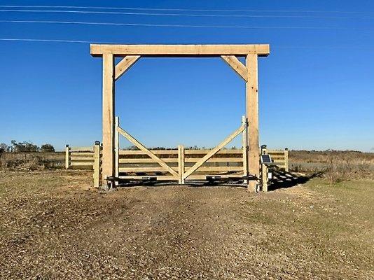 Automated ranch gate with oak header and 4-board fence apron.