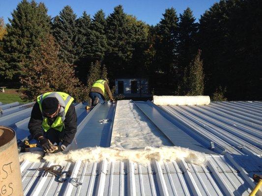 A.C.E. field workers helping correctly install a new metal roof.