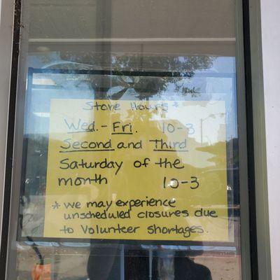 Store hours posted on window.