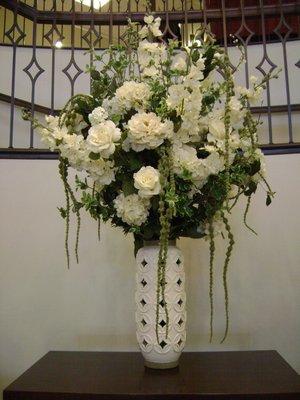 An all white arrangement with peonies, roses and delphinium.