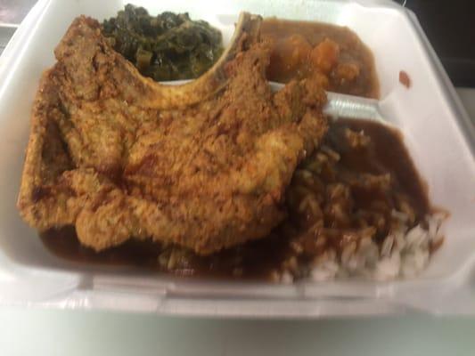 Pork chop dinner with rice and brown gravy, and greens.