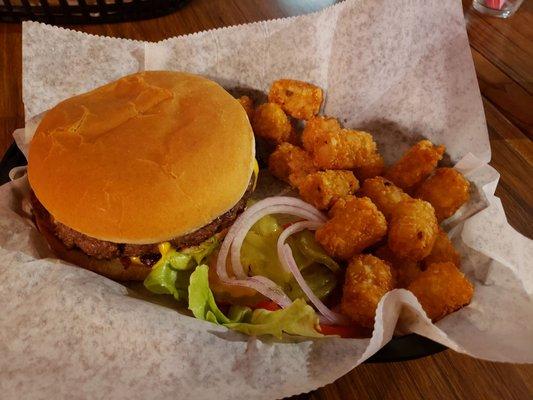 Specialty burger with bacon and cheese and a side of tots