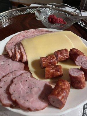 Appetizer plate at home featuring bottom left, the ham with pepper; top left ham& salami, cheese, and bottom right sliced kabonasy.