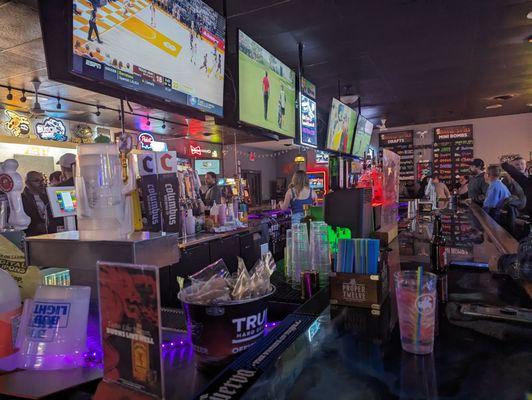 Corner bar seat at back entrance. Four TV's on each side, plugs under the bar. Draft list on the wall.