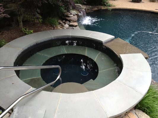 Hand cut and set stone to create a spa with a waterfalls into the swimming pool.