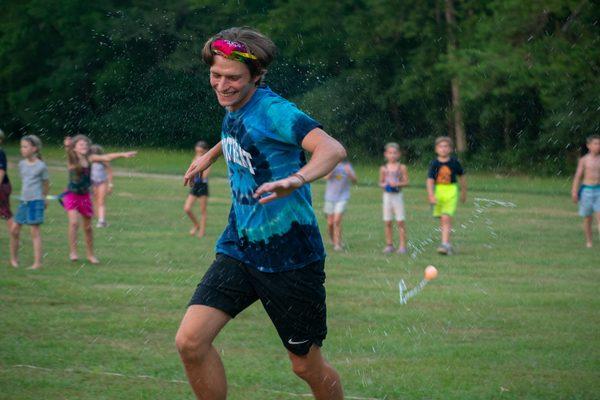 Counselor and campers play water games.