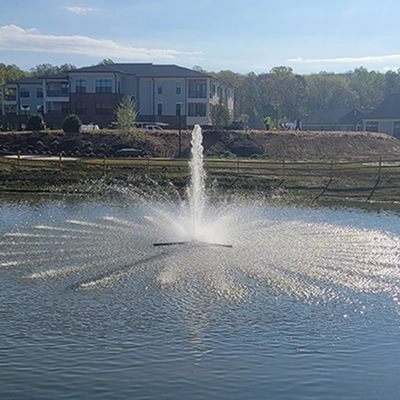 Apartment complex with a fountain in its pond