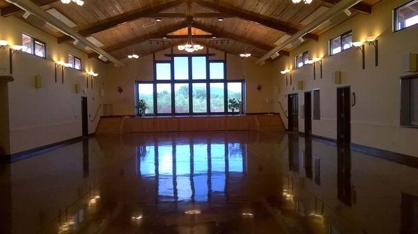 Looking west in the Great Hall at the stage & large windows looking at the coastal range mountains.