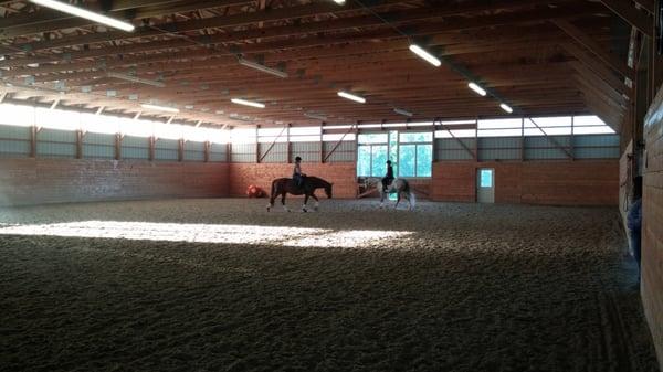 Two boarders cooling down their horses in the indoor arena.