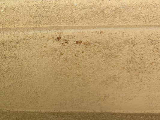 Stains on stucco indicating roof leak into enclosed soffit