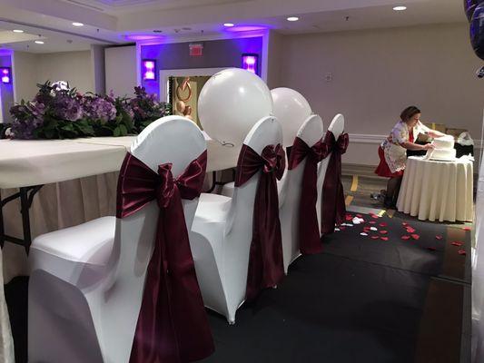 Head table with white spandex chair covers and sangria satin sashes