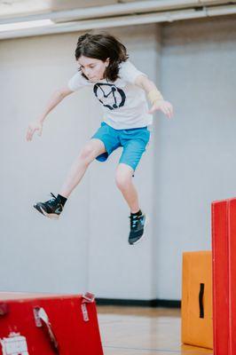 Kids class student, jumping and landing safely on our custom training equipment