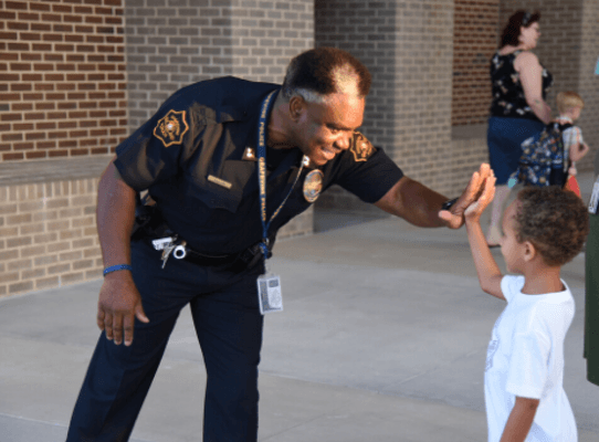 Captain giving high five to student at school