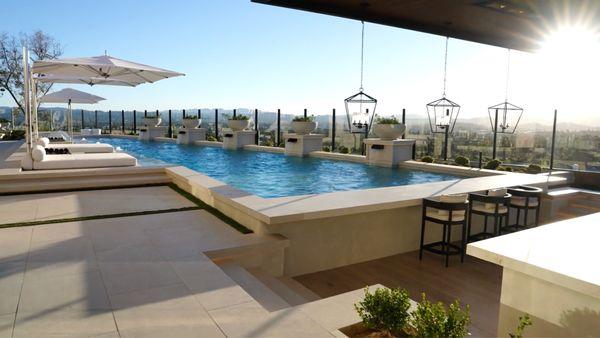 Custom pool with large baja shelf, in water day beds, umbrellas, sunken outdoor kitchen with cantilever roof