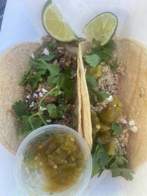 One pork and one chicken taco with green chili sauce, topped with cilantro and queso fresco, no onions as requested.