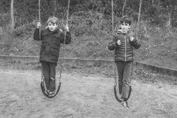 The Stone family boys playing on swings for dramatic family photo.