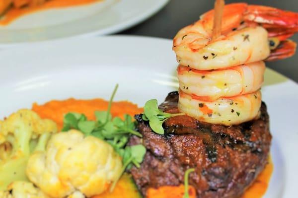 Plated Dinner with Grilled Sirloin w/ prawns, Mashed potatoes sitting on a butternut squash puree