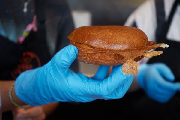 Worker holding freshly made gelato sandwich.  Gelato is already in the center.