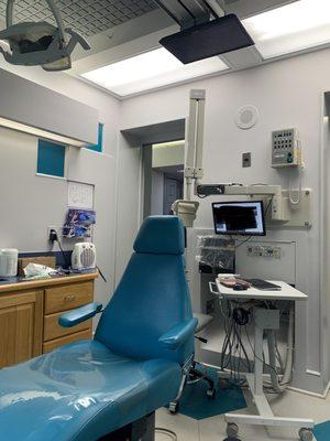 Exam room, kid-sized chairs and TV's mounted to ceiling with Disney movies playing