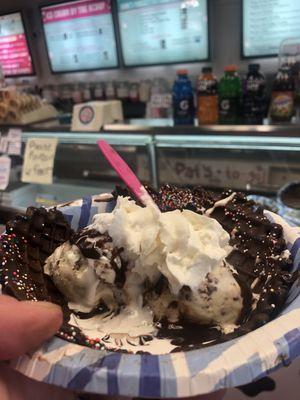 Two scoop sundae in a chocolate waffle bowl. Shown in the background is behind the counter area and the ice cream case up front.