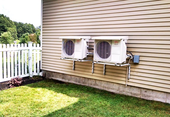 Dual Mitsubishi heat pump condenser units outside of a home in Westbrook.