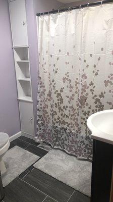 Same bathroom finished with new tile floors, built in linen storage, relocated toilet, window delete and new vanity with sink.