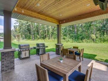 a covered patio with tables and a barbecue grill