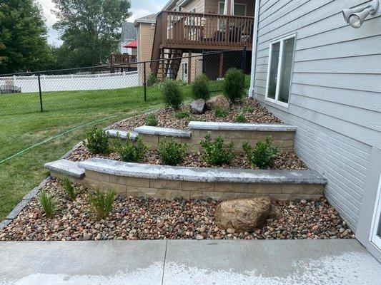 Rock garden bed with edging, two levels of retaining walls with decorative boulders and softscapes in Palmyra, NE.