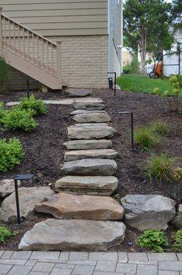 Boulder steps coming up to house from back yard and garden design