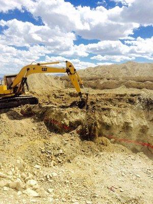 Using an excavator to remove a couple feet of overburden to expose the trilobite fossil ground for collection.