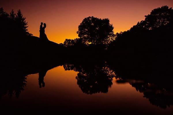 Silhouette of a bride and groom at sunset on their wedding day.