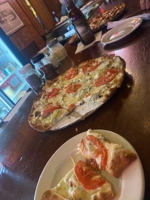 Cheese pizza added some veggies. Meat pizza in background.