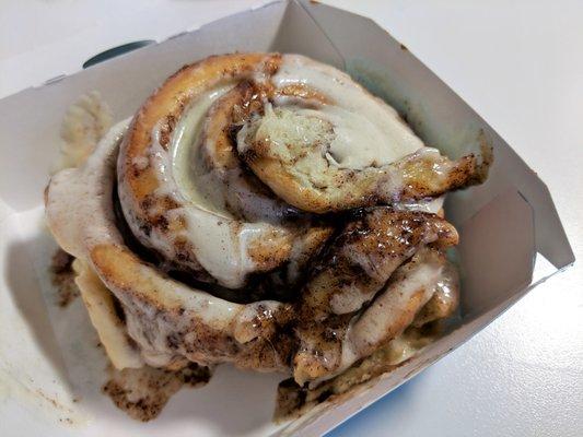 Tender cinnamon roll with a pool of creamy frosting filling every crevice.