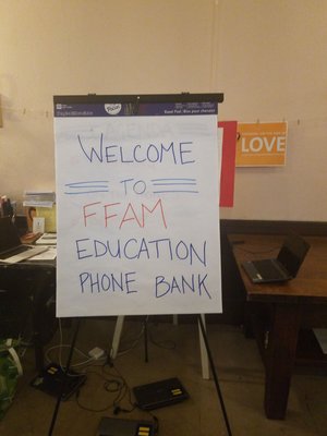 Sign on easel reads "Welcome to FFAM Education phone bank" and the yellow sign on the wall reads "standing on the side of love"