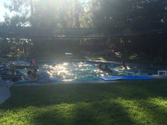 Overcrowded pool and hot dirt cement area parents watch from.