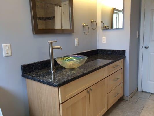 Vanity with vessel sink, granite top and shaker cabinetry.