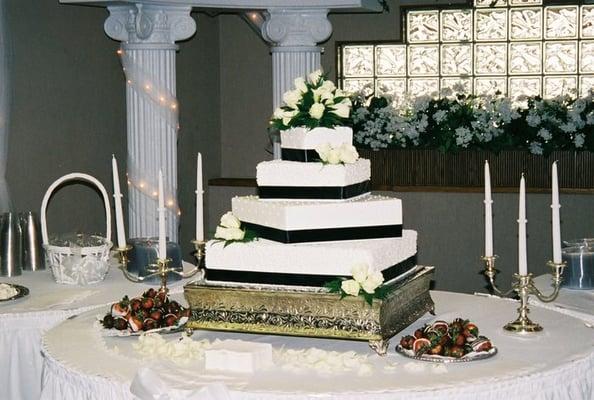 Offset square and fresh cream roses are a perfect blend with the elegant black ribbon on this wedding cake.