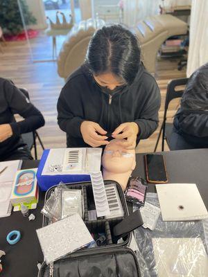 Student is learning how to safely apply eyelash pads.