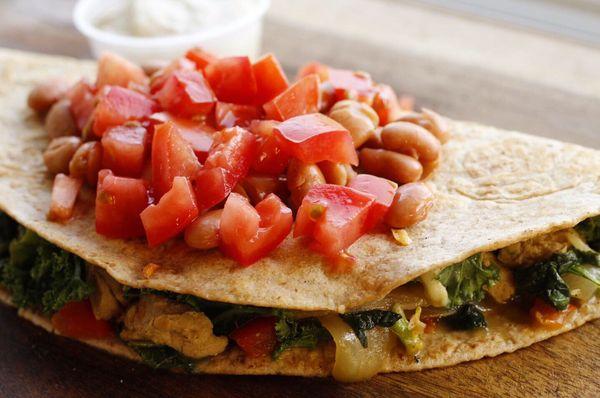 Tofu chick'n quesadilla w/ kale, onions, peppers, tomatoes, pinto beans & side of vegan sour cream.