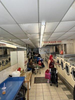 Patrons doing laundry in coin operated machines.