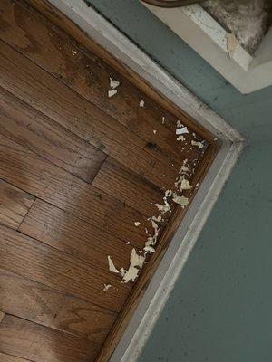 Pile of wallpaper remnants behind fridge.