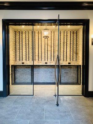 1/2" clear tempered glass wine cellar with a matte black perimeter frame and custom wine barrel handle.