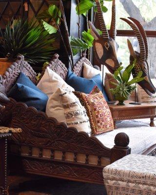 A carved Indian daybed and masks on stands from Burkina Faso.