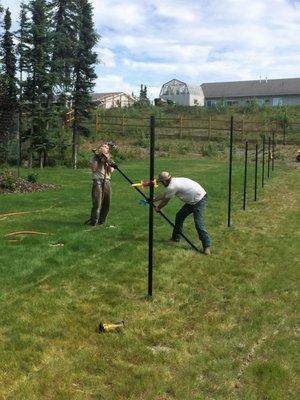 Loading 150 lb pneumatic fence post driver onto a chainlink fence post.